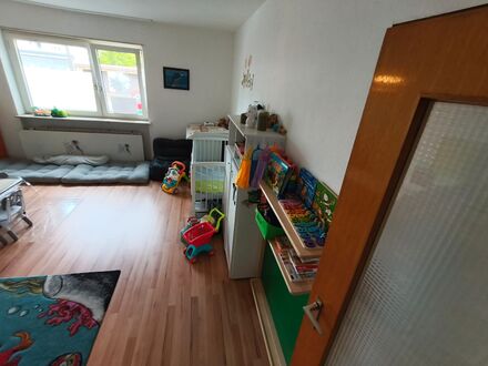 Spielzimmer mit Bücherregal voller Kinderbücher, Puppenwagen und Kuschelecke am Fenster
